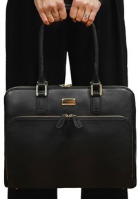 Zwarte leren tote bag met twee handvatten aan de bovenkant, voorzien van gouden hardware, dubbele ritsvak aan de voorkant, een gladde textuur en rechthoekige vorm.