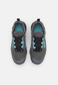 Zapatos exteriores grises con parte superior de malla y acentos turquesas, cordones negros y una suela texturizada. Diseñados para confort y tracción.