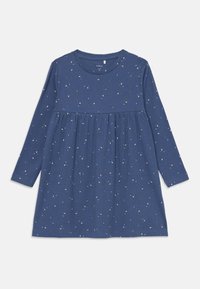 A kék bordás hosszú ujjú ruha fodros derékkal és elszórt virágmintákkal rendelkezik, amelyek apró fémes kiegészítőkkel díszítik az anyagot.