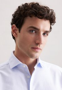 Lichtblauw overhemd met knopen, voorzien van een kraag, met een gladde textuur en subtiele stikdetails. Korte mouwen, eenvoudige design.