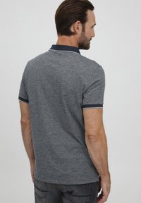 Sivý polokošeľa s textúrovanou tkaninou, s námorníckym golierom a akcentmi na rukávoch, zobrazená zozadu na modeli.