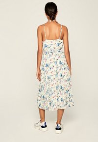 Kwiecista sukienka bez ramiączek z dopasowanym gorsetem, warstwową spódnicą i lekkiego materiału. Posiada niebieskie, różowe i zielone wzory kwiatowe na kremowym tle.