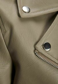 Giacca in pelle verde oliva con dettagli in metallo argentato, inclusi bottoni a pressione e zip, con una finitura testurizzata e leggermente opaca.