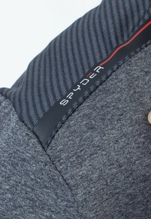 Grey sweater with ribbed dark grey shoulder, featuring a black logo label with "SPYDER" in white and red accents. Smooth texture overall.