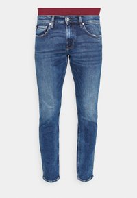 Blå denimjeans med tapered fit, blekt tvätt, femfickdesign, knäppning och synlig sömnad längs sömmarna.