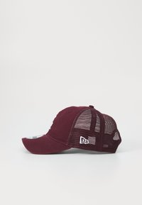 Cappellino da baseball bordeaux con visiera curva, retro in rete e accenti di logo bianchi. Costruzione in tessuto morbido, design strutturato per un aspetto aderente.