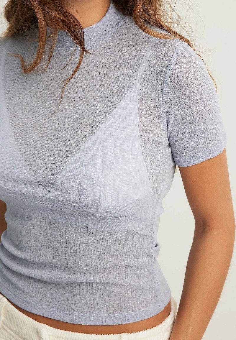 Ljusblå ribbad topp med kort ärm och hög halsringning, med en semigenomskinlig textur, som har en figursydd design och ett subtilt triangulärt mönster.