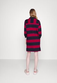 Abito a righe navy e rosse con colletto, maniche lunghe e taglio dritto. Il retro presenta righe orizzontali e un orlo uniforme.