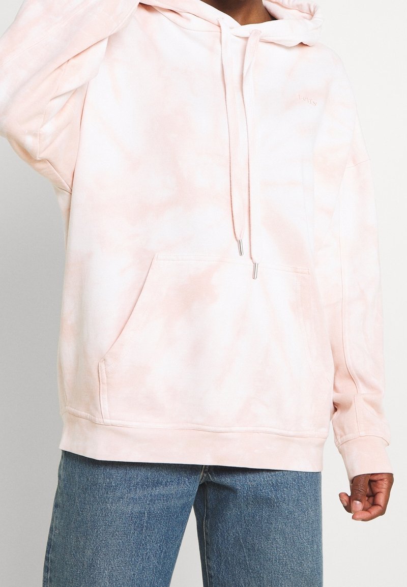 Růžová mikina s tie-dye vzorem vyrobená z měkké látky, s přední kapsou, kapucí se stahovací šňůrkou a žebrovanými manžetami. Jednoduchý, volný střih.