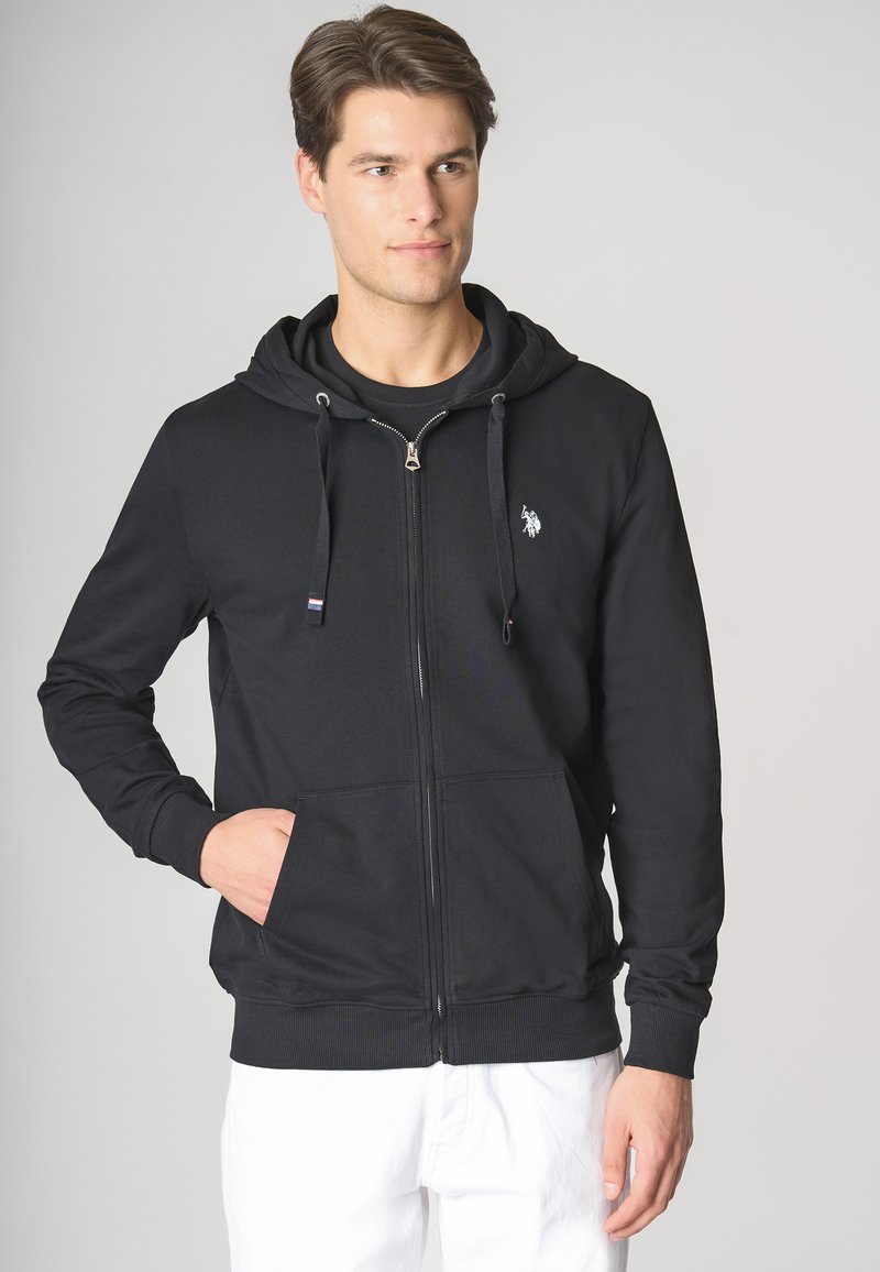Felpa nera con zip realizzata in tessuto morbido, con tasca frontale, cappuccio con cordino e piccolo logo ricamato sul petto.