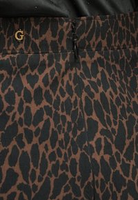 Ruskea ja musta eläinprinttihame näkyvällä vetoketjusulkimella, jossa kultainen "G"-embleemi vyötärön läheisyydessä. Kankaan pinnassa on tekstuuria.