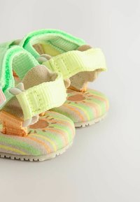 Bunte Sandalen mit weichen grünen Riemen, einer gemusterten Innensohle mit Streifen in Pastellfarben und einer strukturierten Sohle für besseren Halt.