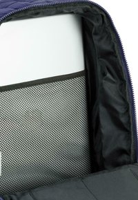 Bolsa exterior acolchada de color azul oscuro con un bolsillo de malla en su interior. El interior presenta un forro de tela negra suave y un panel blanco.