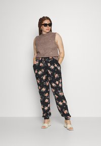 Top tricotat fără mâneci de culoare marron, cu broderie florală, asortat cu pantaloni negri cu imprimeu floral, având un brâu elastic și buzunare. Sandale cu toc pătrat de culoare albă.