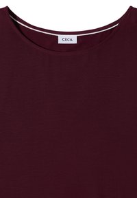 T-shirt rouge foncé à col rond avec une étiquette blanche portant l'inscription "CECIL" centrée à l'intérieur du col.
