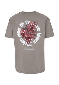 Tricou din bumbac gri, cu un grafic pe spate ce prezintă trei cranioane roșii înconjurate de desene cu flăcări și text alb. Mâneci scurte, gât rotund.
