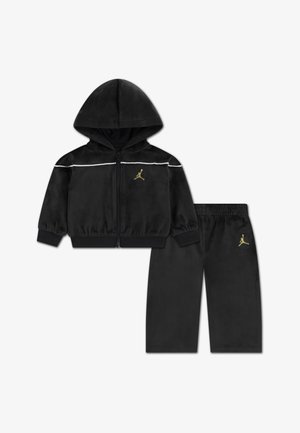 Czarny dres z weluru z rozpinanym kapturem oraz dopasowanymi spodniami. Posiada białe paski i złote logo na obu elementach.