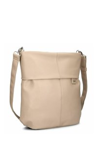 Bolso cruzado de imitación de piel en color beige con solapa plegable, correa ajustable y un sutil detalle de costura. Presenta una etiqueta con el logo en la parte frontal.