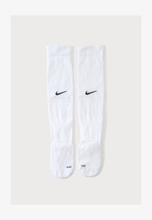 Paire de chaussettes blanches montantes Nike avec logos swoosh noirs et étiquettes de taille sur les parties pieds, présentées sur fond uni.
