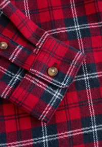 Rote und marineblaue Karomuster-Flanellhemddetails mit einem geknöpften Bündchen, weicher Textur und kontrastierenden weißen und schwarzen Linien im Muster.