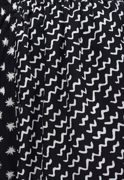 Μαύρο ύφασμα με λευκές ακανόνιστες κυματιστές γραμμές και σχήματα αστέρων που σχηματίζουν δύο διακριτά διακοσμημένα τμήματα.