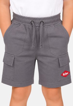 Enfant portant un short cargo gris avec une taille élastique à cordon, des poches latérales et un écusson rouge au logo Lee Cooper, les mains dans les poches.