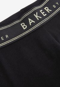 Juodas audinys diržo juostos su tekstu "BAKER" išsiuvinėtu sidabriniu siūlu. Lygaus paviršiaus tekstūra su kontrastinga audimo krašto detale.