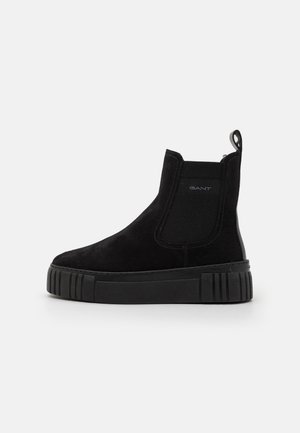 Botte Chelsea en daim noir avec semelle épaisse en caoutchouc, panneau latéral élastique, languette à talon et logo discret "GANT" sur le côté supérieur.