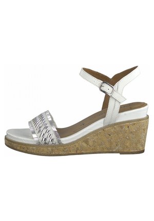 Białe sandały na koturnie z korkową podeszwą, metalicznie pleciony pasek na palcach oraz regulowany pasek na kostkę z klamrą.