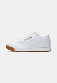 Sapatilhas Reebok de cano baixo brancas com sola de borracha, atacadores laterais e logótipo Reebok com a bandeira do Reino Unido no painel lateral.