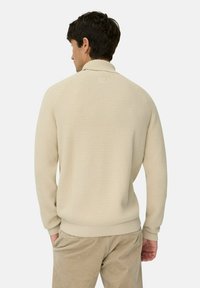 Beige strukturierter Pullover-Sweatshirt mit hohem Kragen, gerippten Bündchen und Saum, von hinten an einem Modell gezeigt, das beige Hosen trägt.