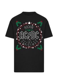 Zwart katoenen T-shirt met een cirkelvormige grafische afbeelding met de tekst "AC/DC", kerstverlichting, hulstbladeren en een beer met een kerstmanmuts.