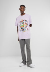 Purple cotton t-shirt featuring a colorful graphic print with cartoon characters, paired with gray trousers and white sneakers.