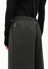 Dunkelgraue Jogginghosen mit weichem Material, elastischem Bund und Seitentaschen, kombiniert mit einem schwarzen Langarmshirt.