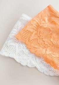 Kantstof in oranje en wit. Het oranje stuk heeft bloemmotieven en een netachtige textuur, terwijl het witte stuk een fijne, gegolfde rand heeft.