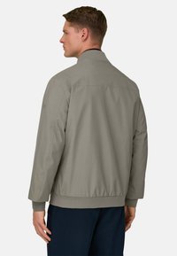 Giacca bomber grigio chiaro con collo arrotondato, polsini e orlo a coste; tessuto liscio con design minimalista e senza motivi o accenti visibili.