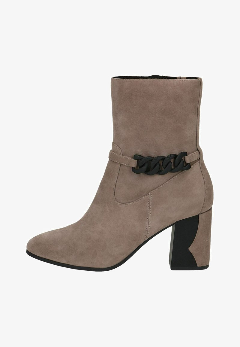 Beige ruskindsankelstøvle med blokhæle, med en sort kædeaccent omkring anklen og spids tå-designet. Glat tekstur.