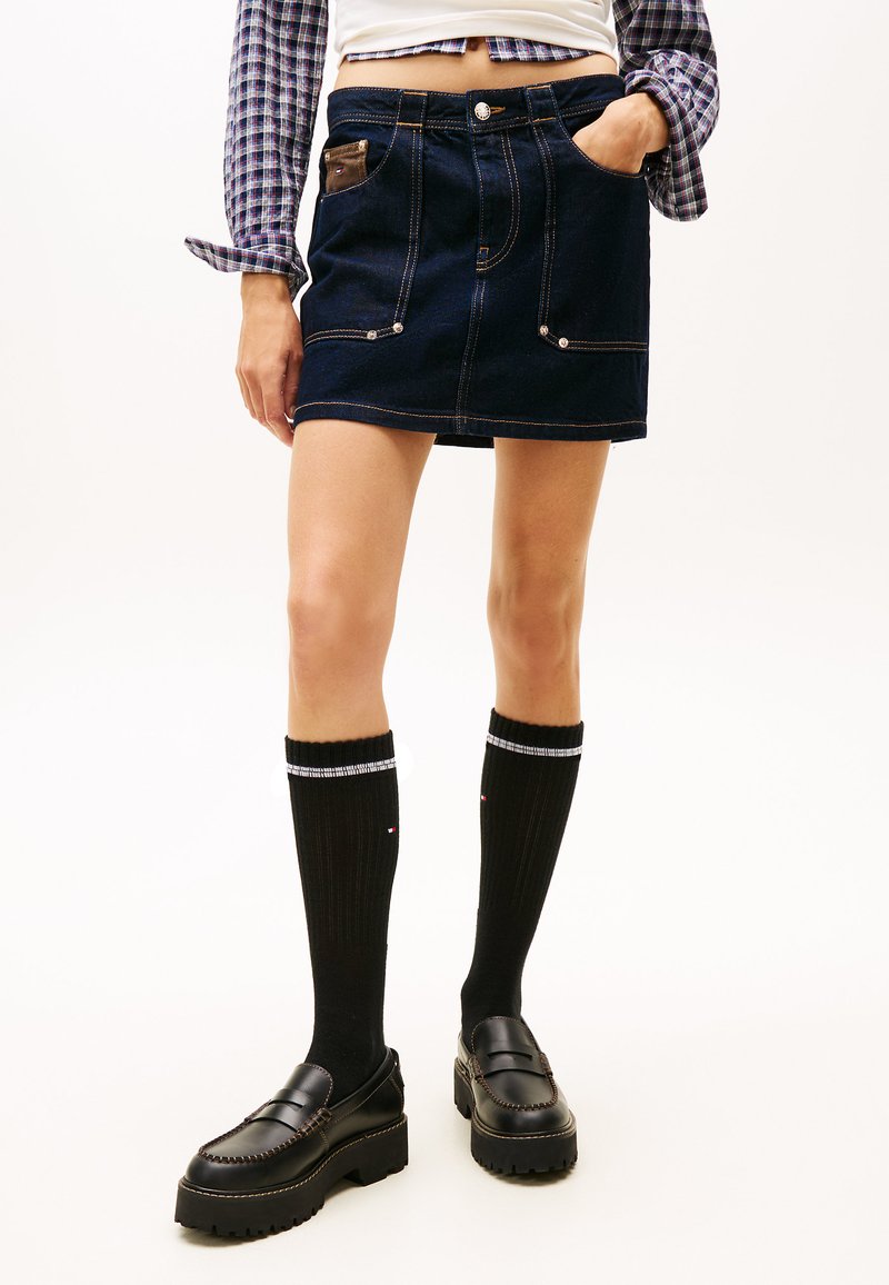 Tumesinises toonis teksaseelik heledate õmblustega, ees taskud ja pruun detail. Sobitatud mustade põlvikute ja paksu tallaga mokassiinidega.