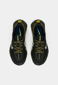 Μαύρα και πράσινα παπούτσια τρεξίματος με πουά σχέδιο, υφασμάτινο επάνω μέρος και κίτρινες λεπτομέρειες. Διαθέτουν μπλε εσωτερική επένδυση και λευκή σόλα.
