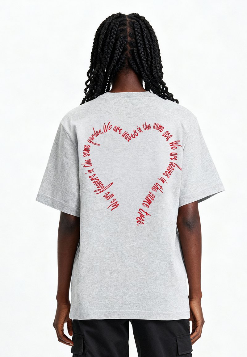 Szary, oversize'owy t-shirt z krótkimi rękawami. Na plecach znajduje się czerwona, kursywna napisana tekst w kształcie serca. Miękka, przypominająca bawełnę tekstura.