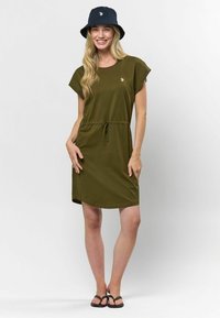 Rochie verde măsliniu cu mâneci scurte și talie cu șnur, confecționată dintr-un material moale. Asortată cu o pălărie tip bucket neagră cu un logo.