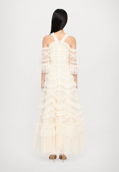 Ivory maxi jurk met gelaagde ruches, doorschijnende off-the-shoulder mouwen en een aansluitend lijfje. Textuurstof met subtiele stippen.