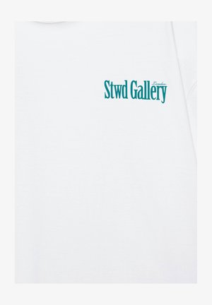 Vêtement blanc avec texte bleu sarcelle "Stwd Gallery" et un plus petit "London" imprimés en haut à gauche.