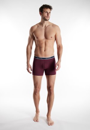 Burgunderfarbene Baumwollboxershorts mit einem schwarzen Bund, der eine weiße Markenzeichnung aufweist, enganliegendem Design und subtiler horizontaler Struktur.