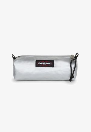 Silver cylindrical pencil case with a black Eastpak logo patch, zip closure, and textured nylon material. Features a black pull tab.