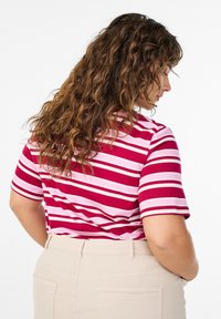 Lühikeste varrukatega, ümara kaelusega triibuline top, millel on vahelduvad burgundi ja roosa triibud. Sobitatud beežide kõrge vöökohaga pükstega. Tekstuur näib sile.