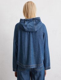 Blaue Denimjacke mit Kapuze, im lässigen Schnitt, langen Ärmeln und kontrastierenden Nähten. Glatte Textur mit leicht verblasstem Finish.