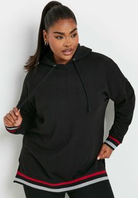 Svart hoodie med en texturerad yta, med dragsko i huvan och en röd och grå randig nederkant och ärmslut. Avslappnad, oversized passform.
