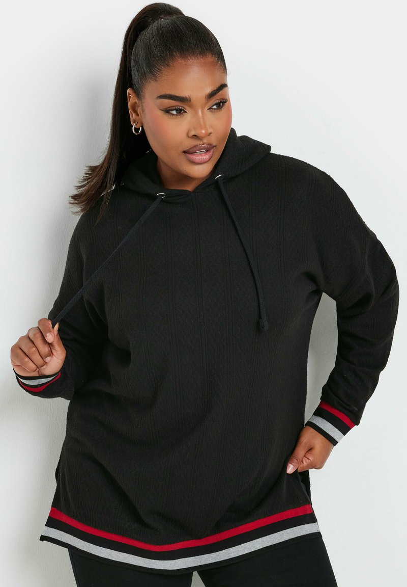 Svart hoodie med en texturerad yta, med dragsko i huvan och en röd och grå randig nederkant och ärmslut. Avslappnad, oversized passform.