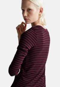 Bordowy i czarny prążkowany dopasowany top z długimi rękawami i okrągłym dekoltem, wykonany z miękkiego, elastycznego materiału.